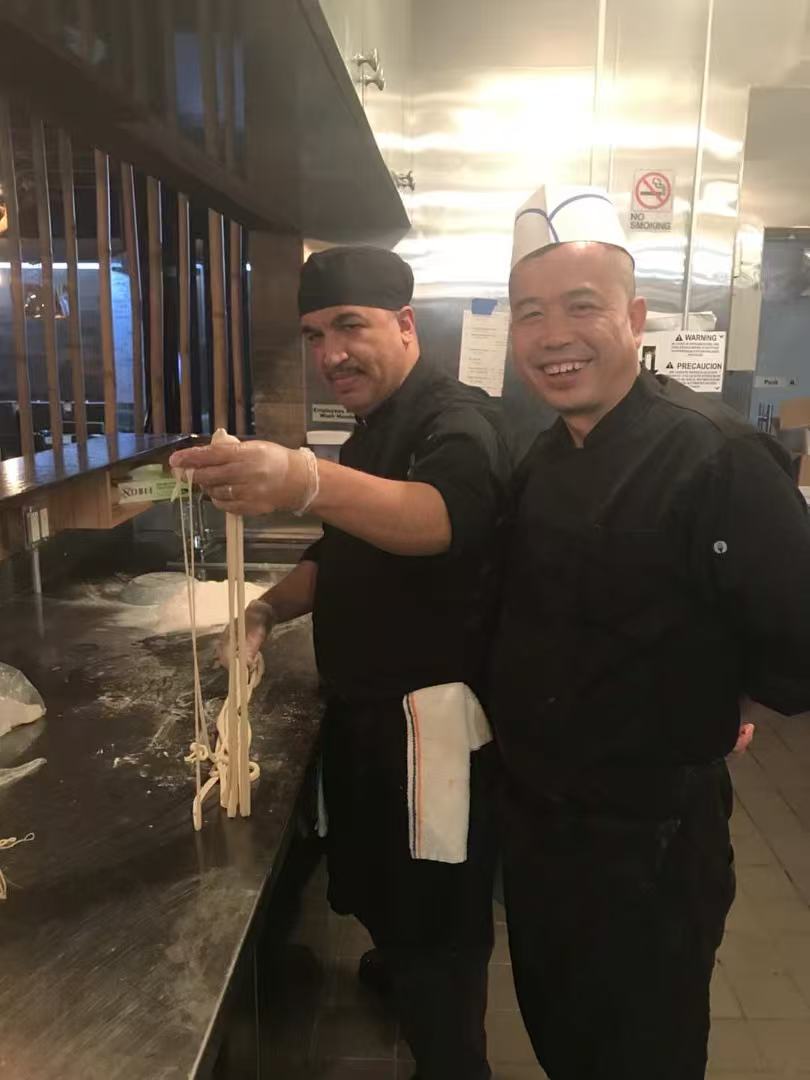 Apprentice holding freshly pulled noodles with the master